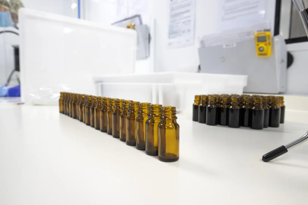 Rows of amber medical cannabis oil bottles lined up on a white laboratory bench